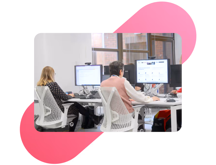 Two professionals working at desktop computers in a modern office, analyzing data and digital platforms.